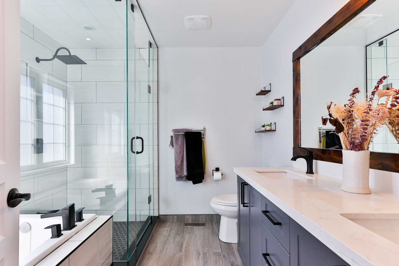 Renovated bathroom with a glass shower, tile surround and a double vanity.