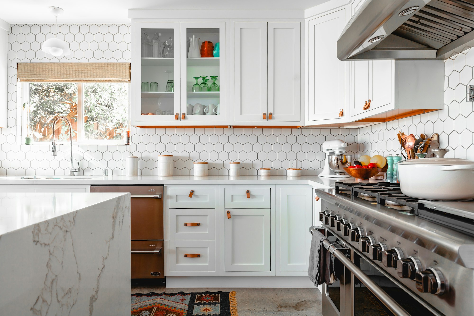 Bright renovated kitchen with white shaker cabinetry, hex tile backsplash and a marble island.